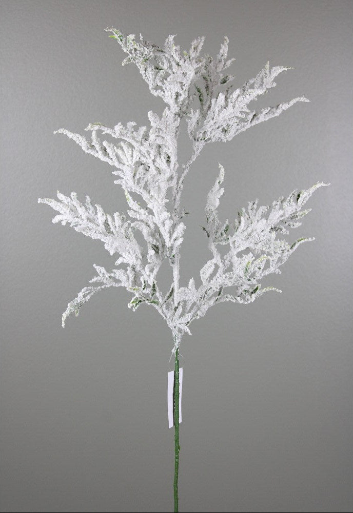 A single artificial frosted branch stem with delicate white flocked foliage on a green stem, photographed against a plain gray studio background.
