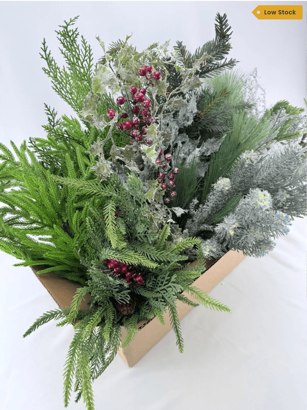 an arrangement of assorted artificial greenery with a low stock tag