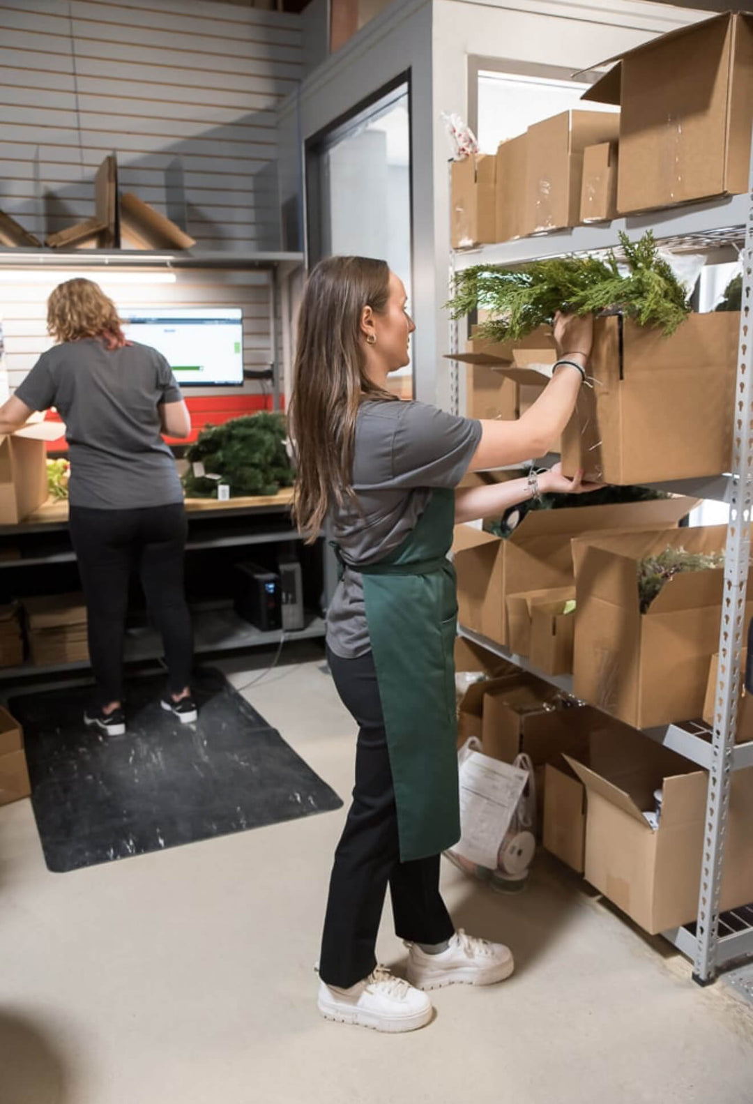 Two people working in a warehouse setting with boxes and plants.